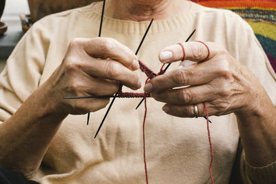 Midsection of elderly woman knitting while sitting at home