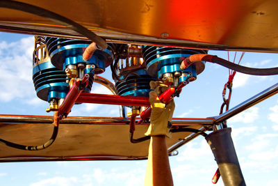 Low angle view of chain swing ride against cloudy sky