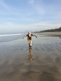 Full length of woman standing on beach against sky