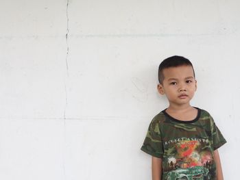 Portrait of boy standing against wall