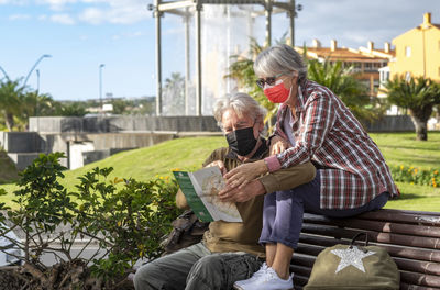 Senior couple looking at map while sitting on bench