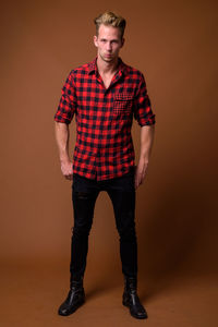 Portrait of young man standing against wall