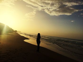 Man standing on beach against sky during sunset