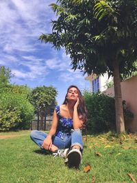 Full length of young woman sitting on field