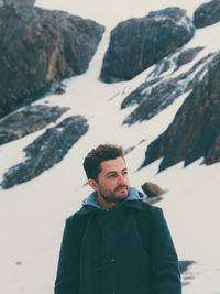 Young man standing on snow covered mountain