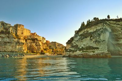 Rock formations by sea against clear sky