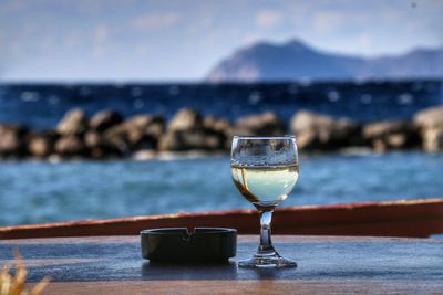 Close-up of wineglass on table against sea