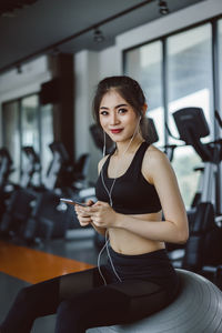 Young woman using phone while sitting on laptop