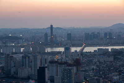 Illuminated cityscape against sky during sunset