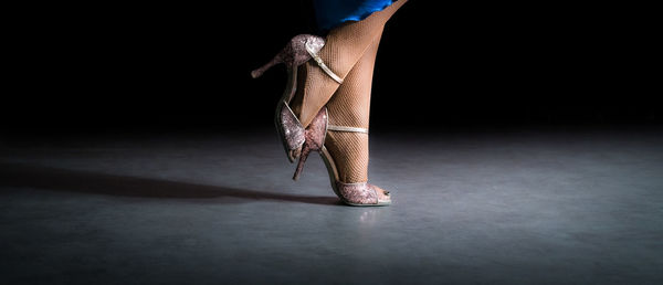 Low section of woman dancing against black background