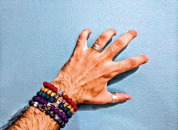 Cropped hand of man wearing bracelets touching on wall