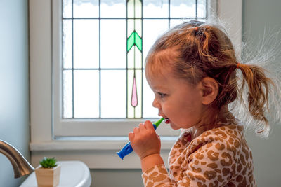 Cute girl brushing teeth at home