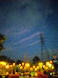 Defocused image of illuminated city against sky at dusk