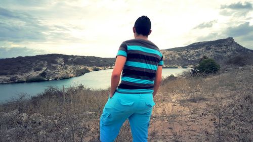 Rear view of man walking on mountain against sky