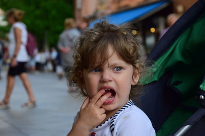 Close-up of cute girl with fingers in mouth looking away