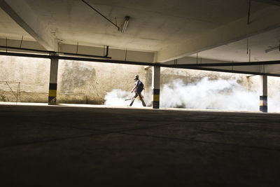 Full length of man spreading smoke while walking in by parking lot