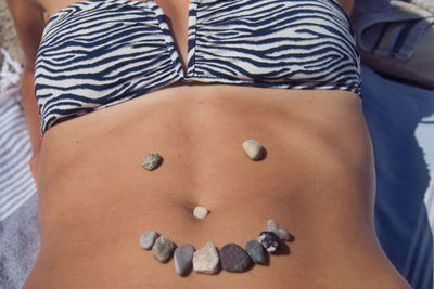 Midsection of woman with stones on stomach