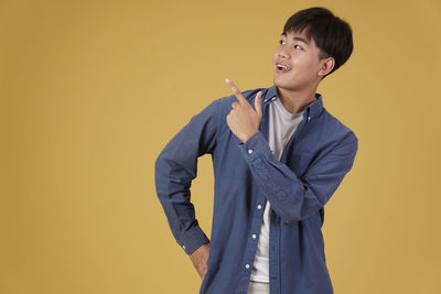 Boy standing against yellow background