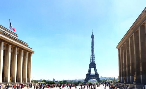 Crowd and eiffel tower against clear blue sky in city