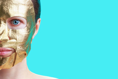 Portrait of young woman with a golden mask on face, skin care concept.