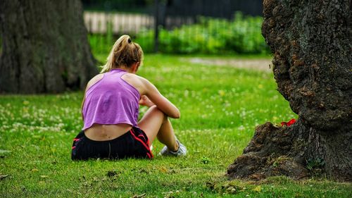 Rear view of girl sitting on grass