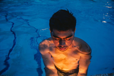 Young man in illuminated swimming in pool