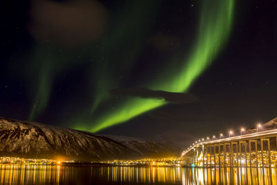 Illuminated bridge over river against aurora borealis