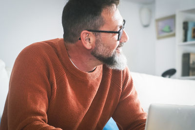 Young man looking away while sitting at home