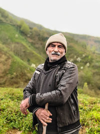 Portrait of man standing on field against mountain during winter