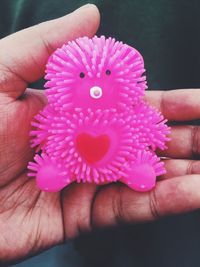 Close-up of cropped hand holding pink flower