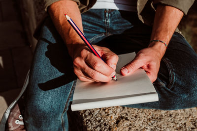 Midsection of man writing on notepad