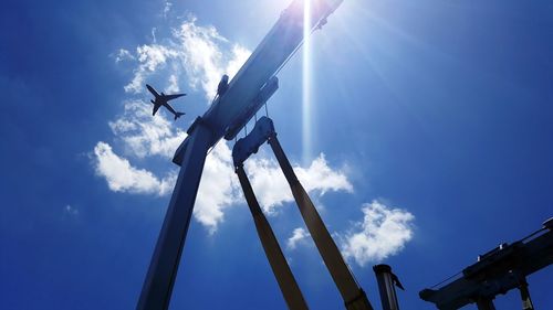 Low angle view of airplane flying against blue sky on sunny day
