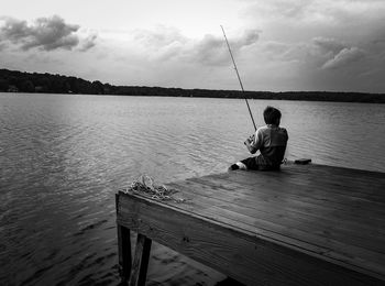 Rear view of man fishing at sea shore