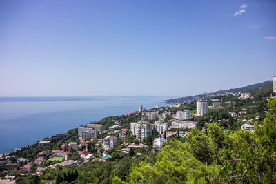 Panoramic view of townscape by sea against clear blue sky