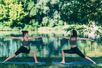 Yoga women by the lake. warrior pose