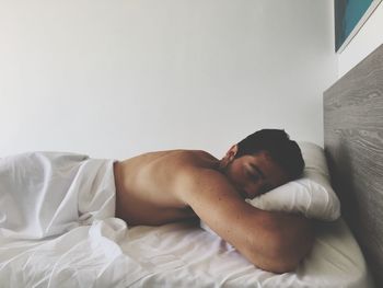 Shirtless man lying on bed