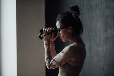 Side view of woman standing against wall