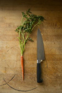 High angle view of carrot and knife on wooden table in kitchen at home