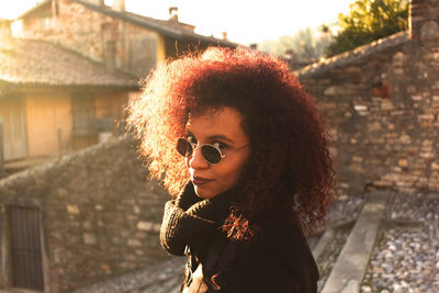 Portrait of woman wearing sunglasses standing against retaining wall