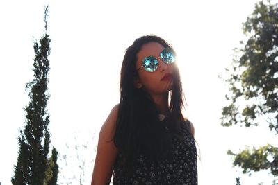 Young woman against trees against sky