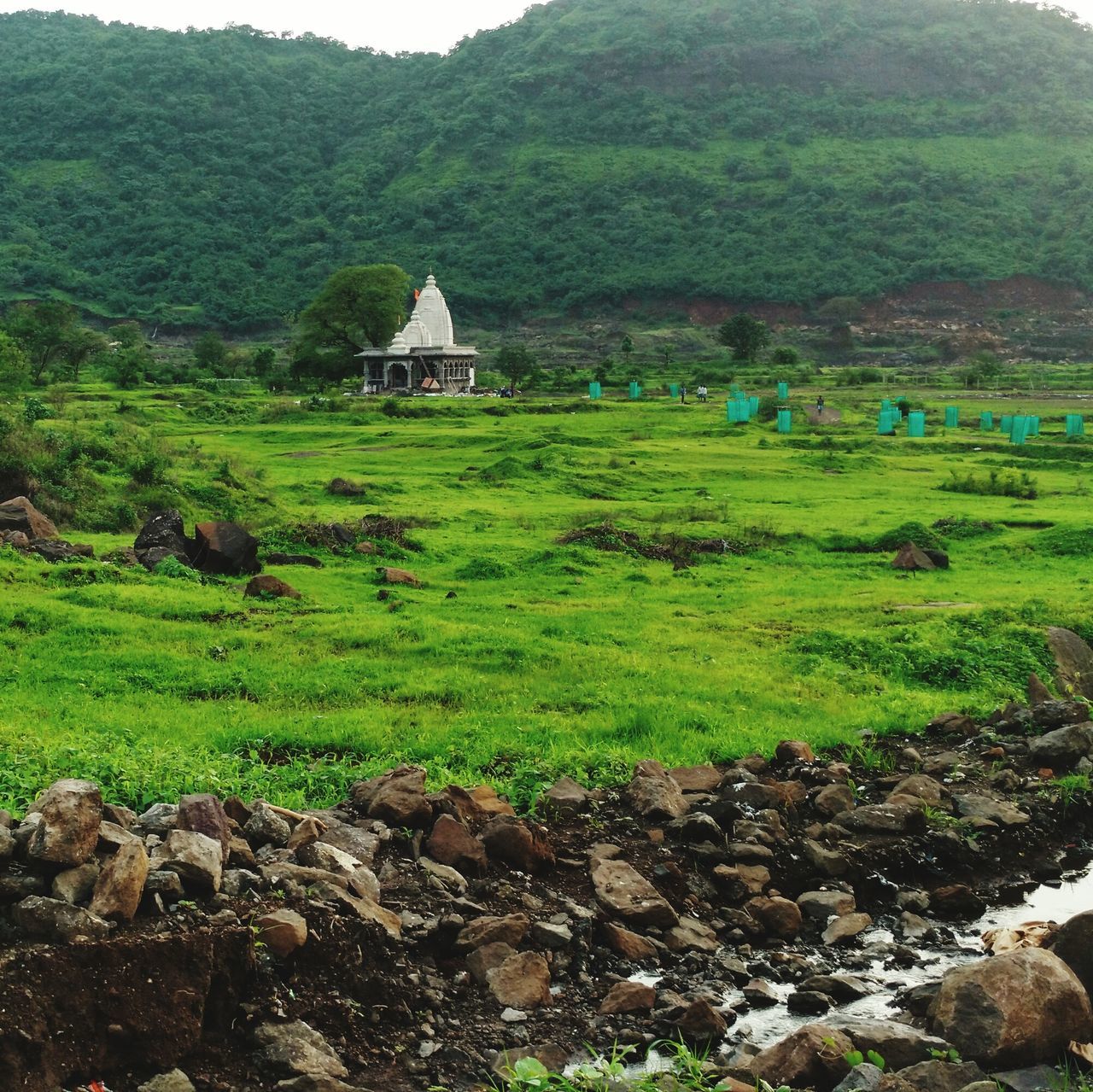 mountain, built structure, architecture, landscape, green color, grass, tranquil scene, tranquility, scenics, beauty in nature, mountain range, nature, hill, non-urban scene, day, growth, sky, outdoors, plant, idyllic, village, rural scene, remote, no people, travel destinations, green, lush foliage