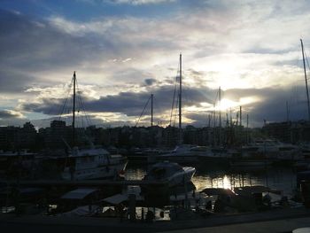 Boats at harbor against cloudy sky