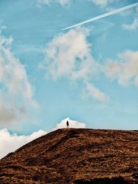 Low angle view of person standing on landscape against sky