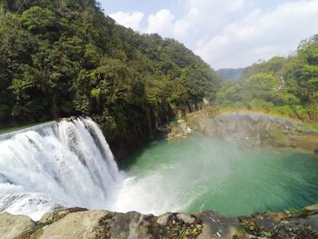 Scenic view of waterfall and rainbow