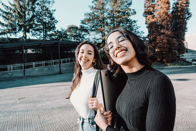 Portrait of smiling female friends walking at college campus