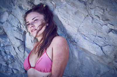 Beautiful woman in bikini standing against rock formation