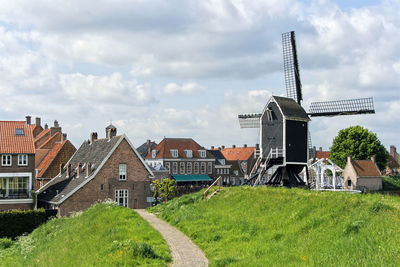 Houses on field by buildings against sky