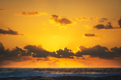 Scenic view of sea against dramatic sky during sunset