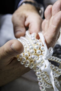 Cropped hands holding pearl jewelry