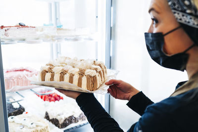 Midsection of woman holding ice cream in kitchen